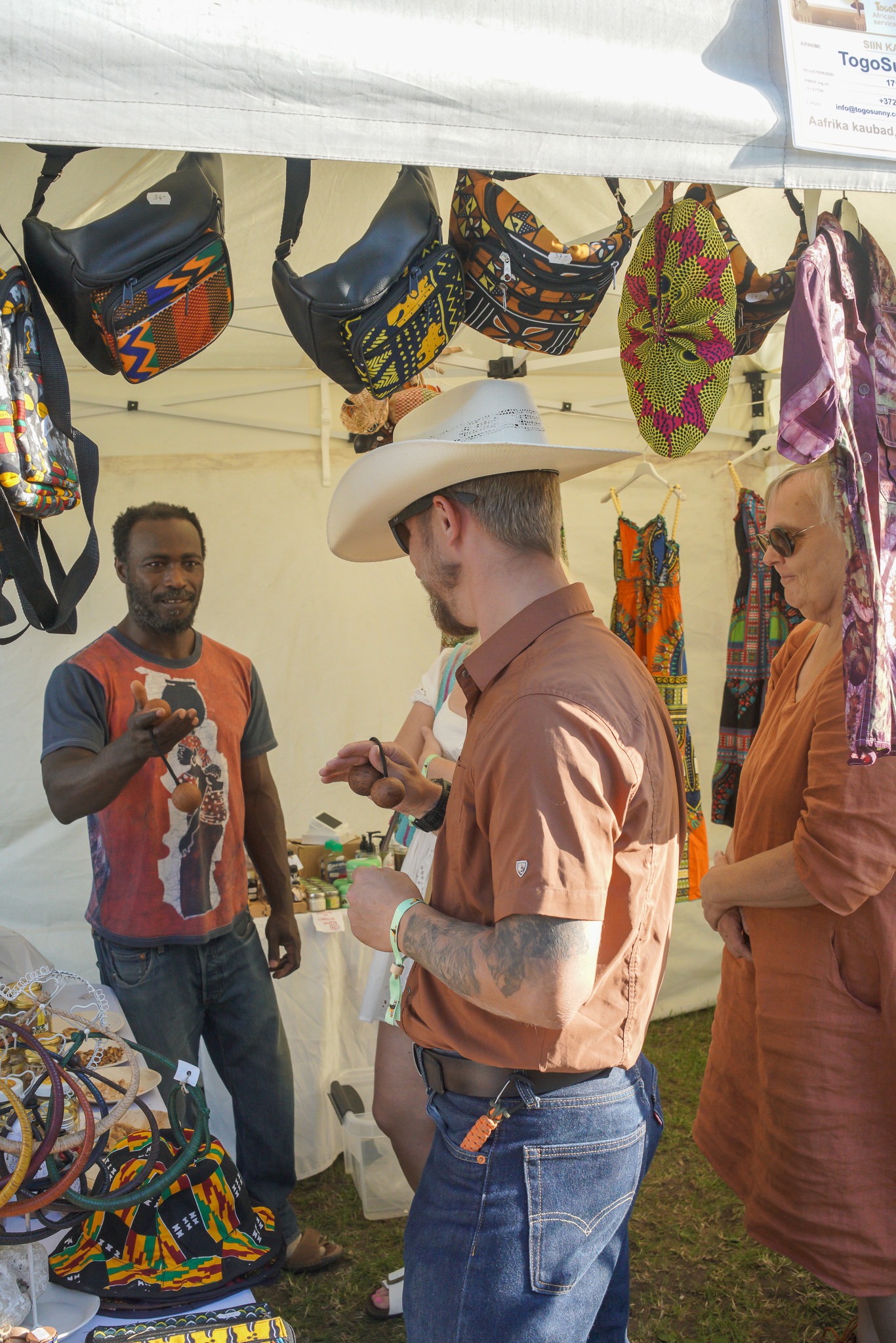 A visitor in a cowboy hat tries a maraca with the seller