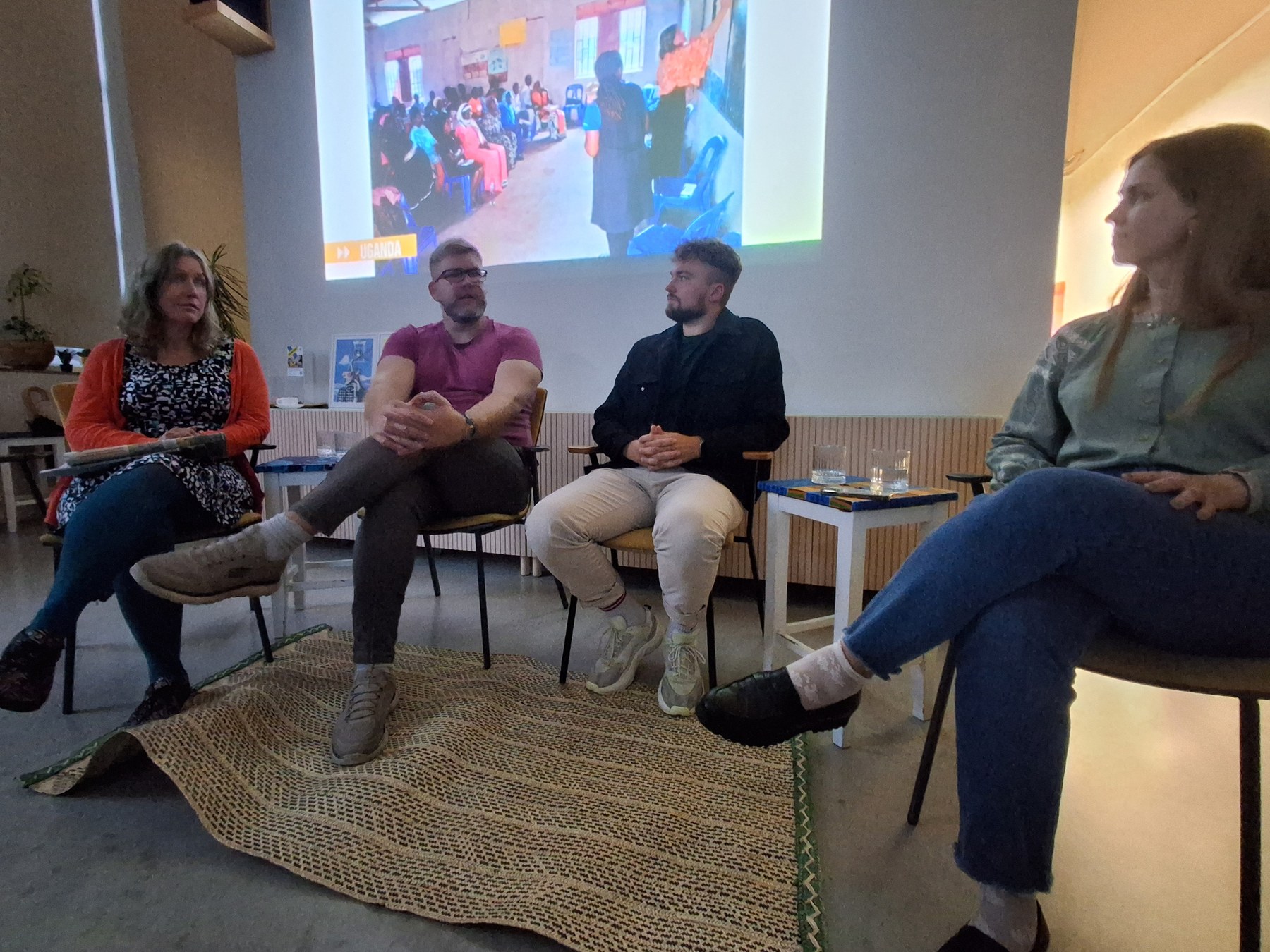 Panel of journalists on stage with a photo from Uganda projected behind them