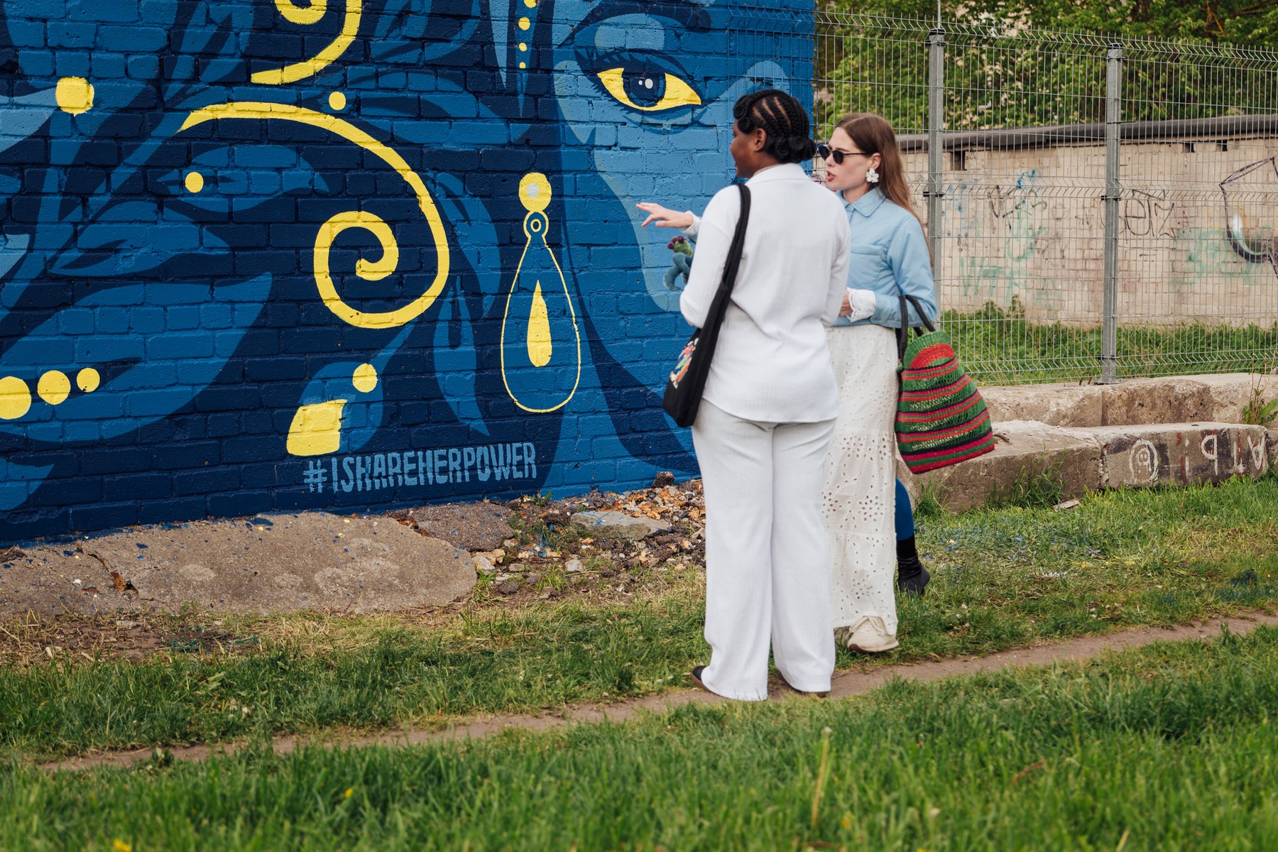 Two women looking closely at the wall's patterns