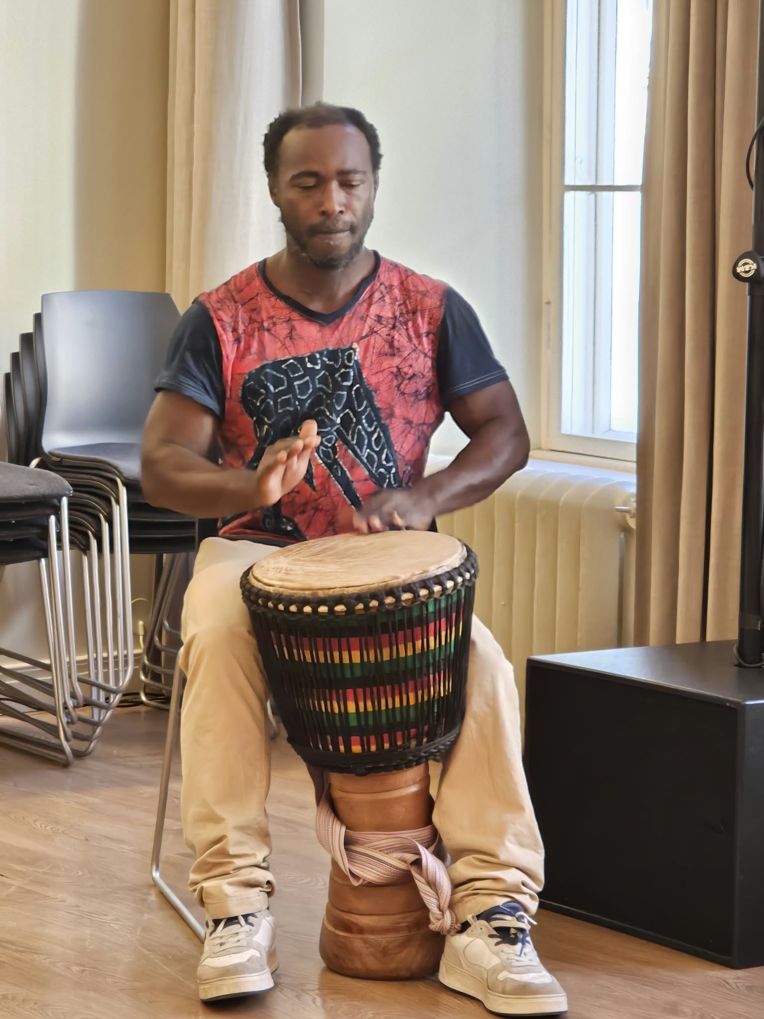 Senam Tsogbe playing the djembe, eyes closed, focused on the rhythm