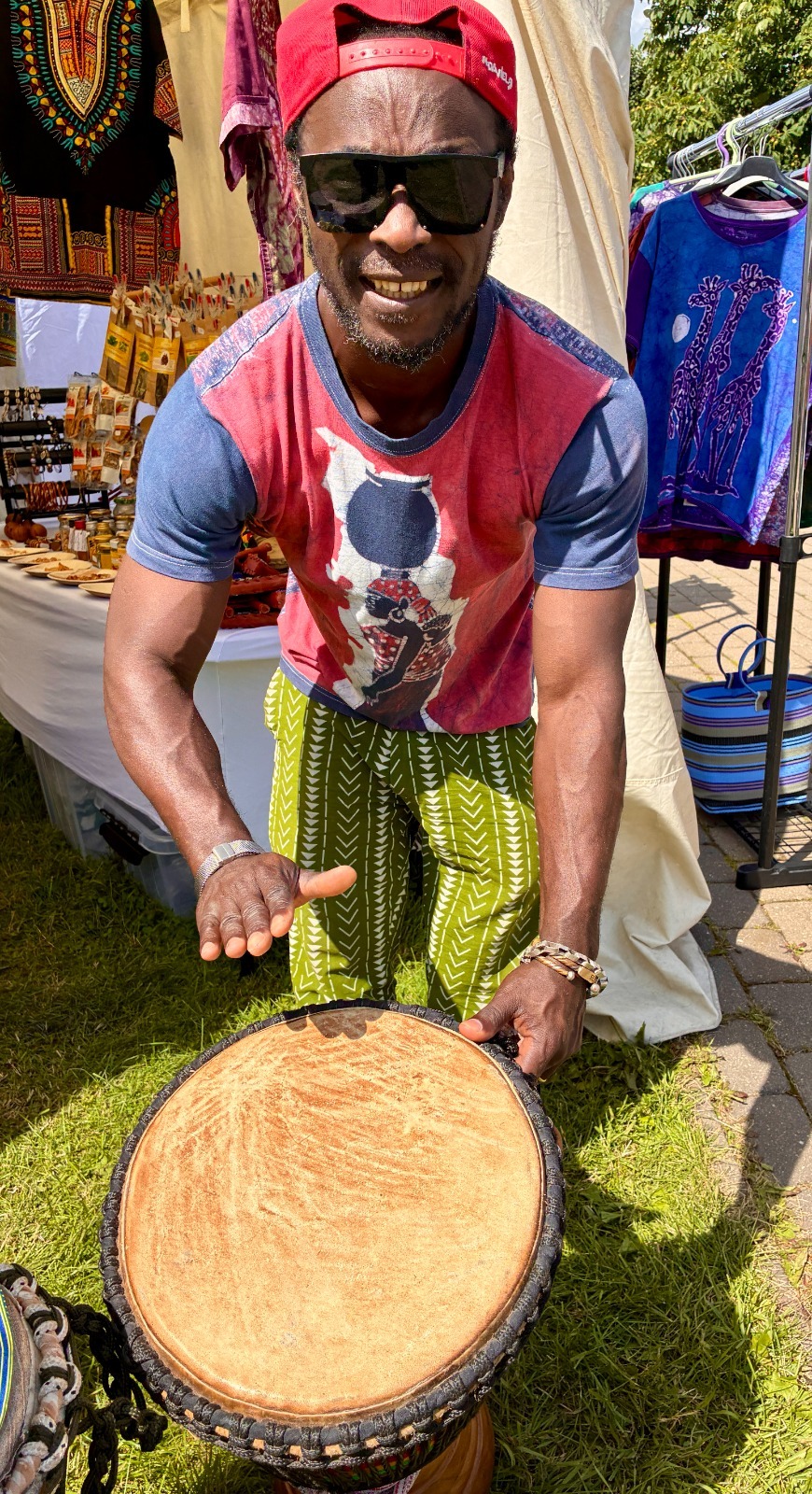 Close view of a hand resting on a single djembe drum outside the tent